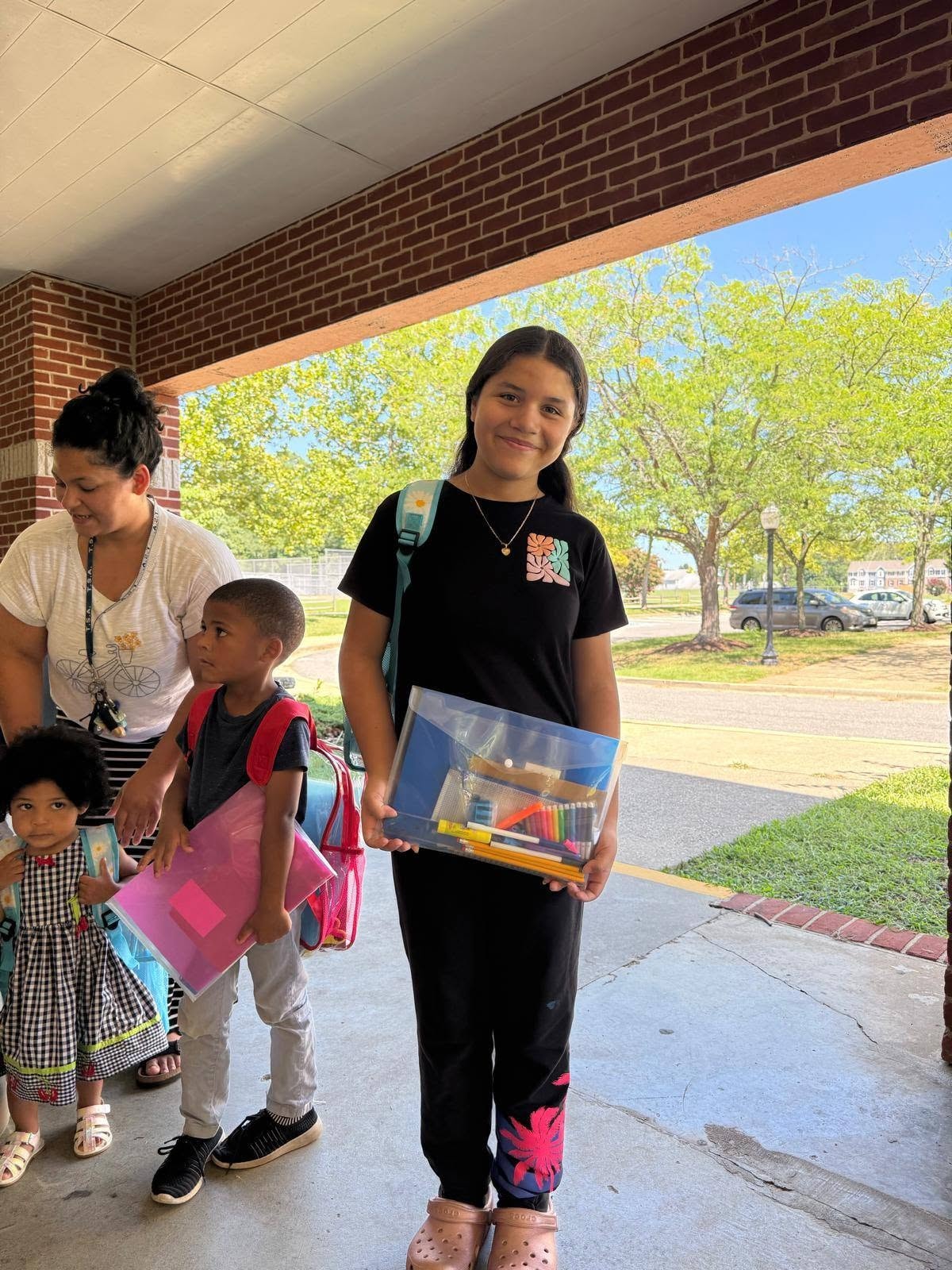 Girl smiling with school supplies and backpack at community event