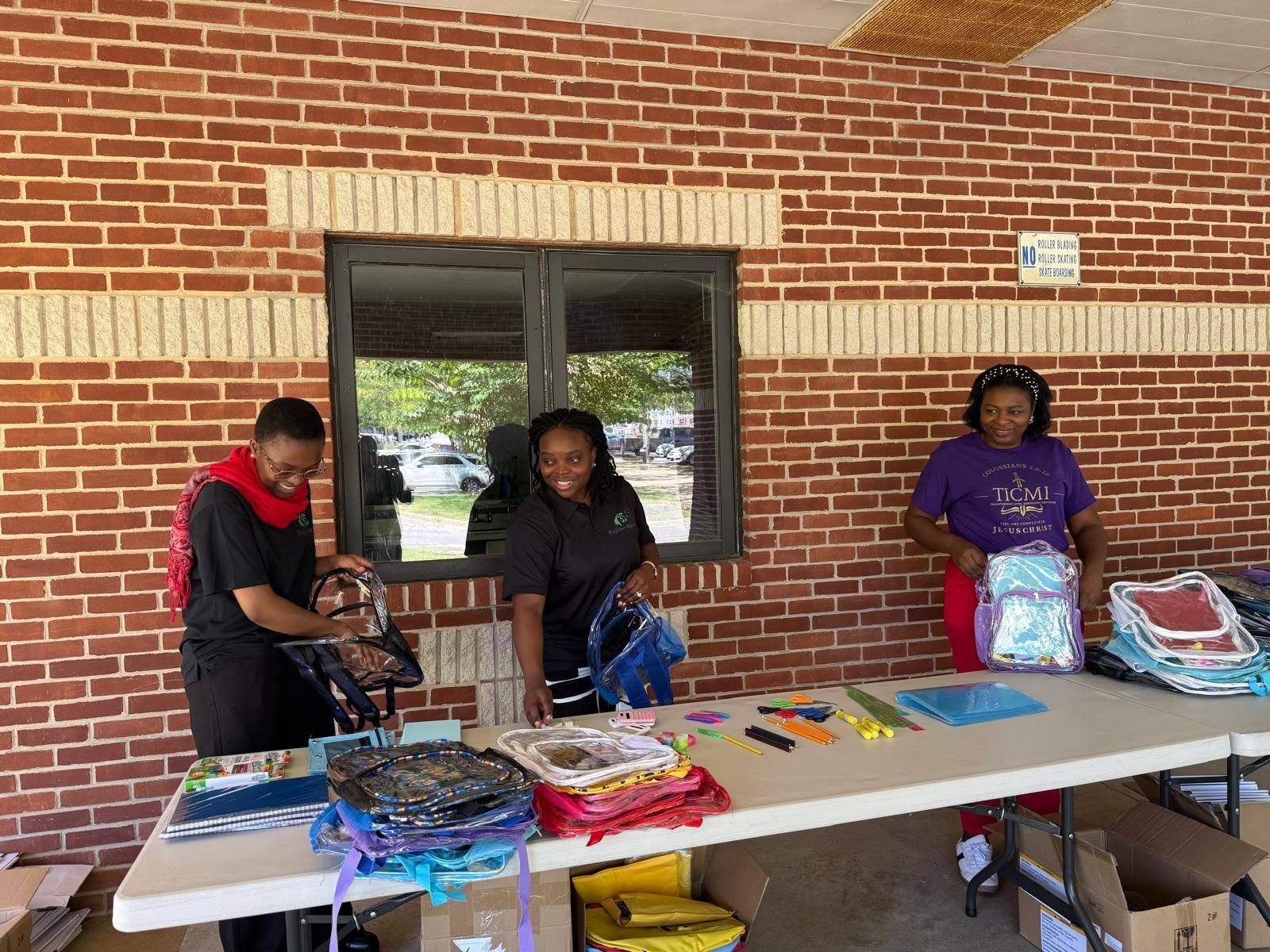 Volunteers organizing backpacks and school supplies at event table