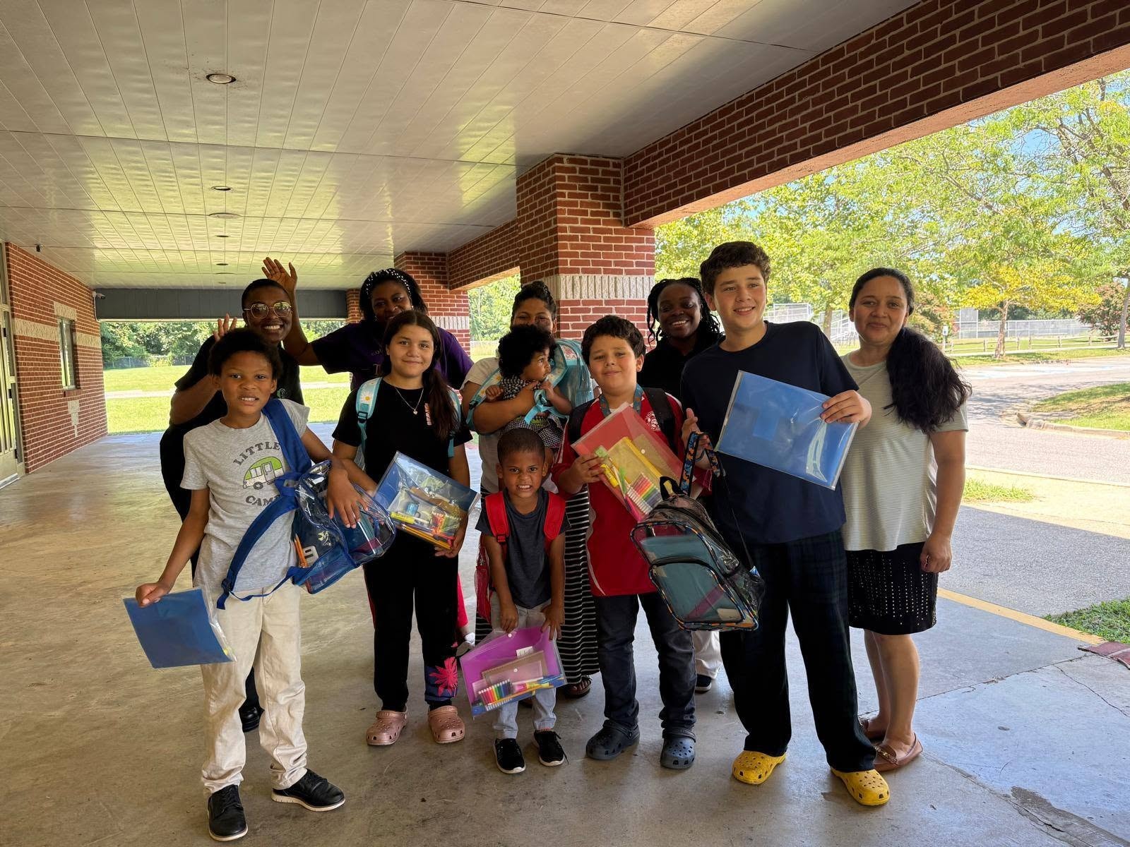 Group of children and families with school supplies smiling together
